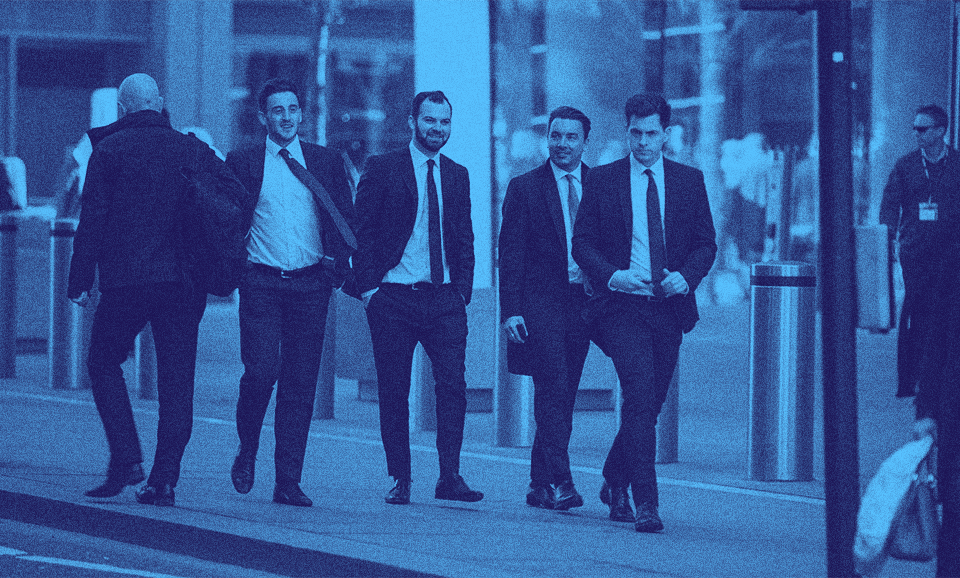 A group of men in suits walking down a street.