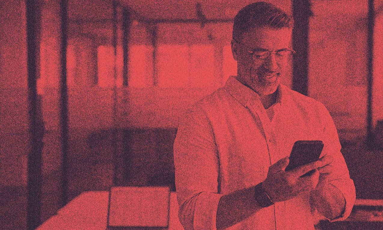 A man looking at his phone smiling.
