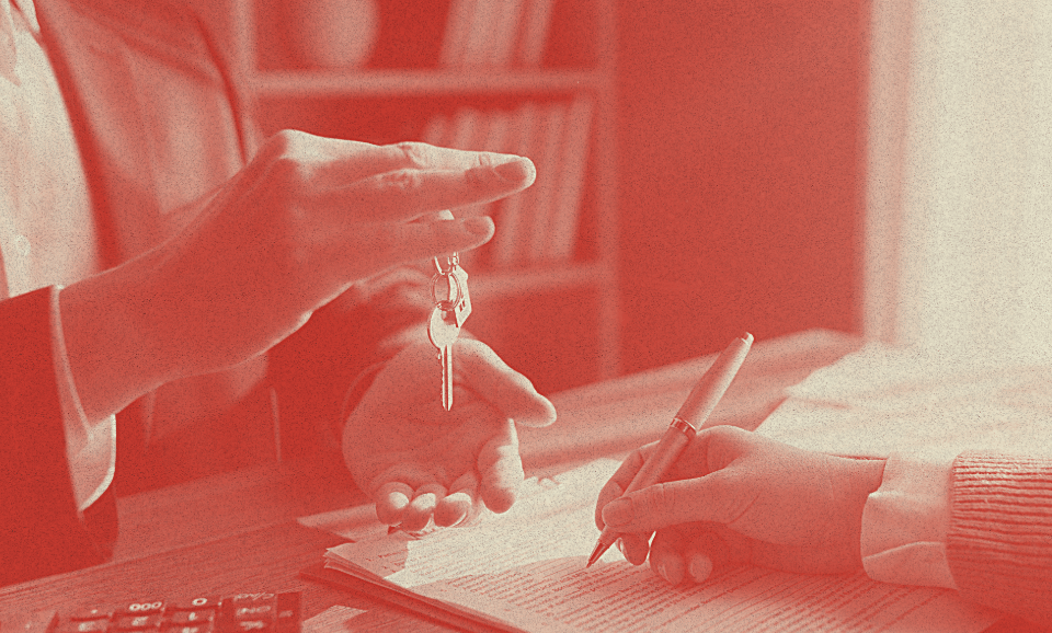 Bir insan, bir masanın üzerindeki elinden anahtar sarkıtmakta.