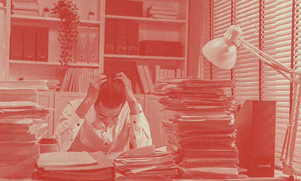 A man sits beside a desk with his between his hands.