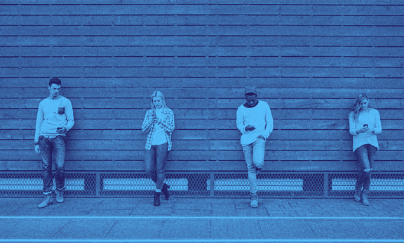 Four people leaning against a wall side by side.