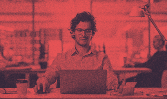 Gözlüklü bir insan, bilgisayarı başında çalışıyor