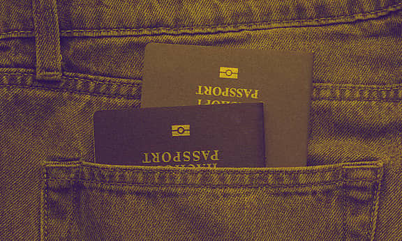 Two passports are seen stacked inside a back pocket of a person's jeans.