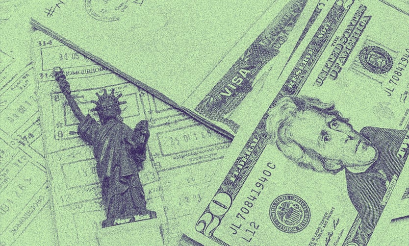 Dollars bank notes and a small model of Lady Liberty on a table.