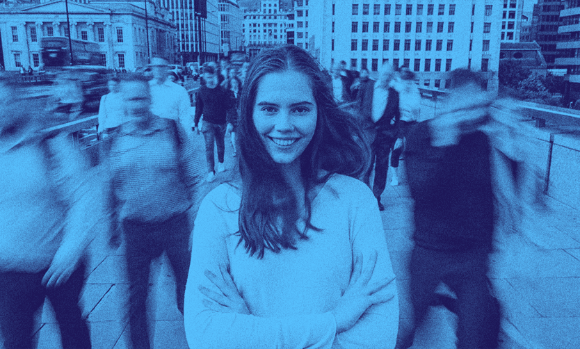 A person smiling amongst the crowd passing by her.