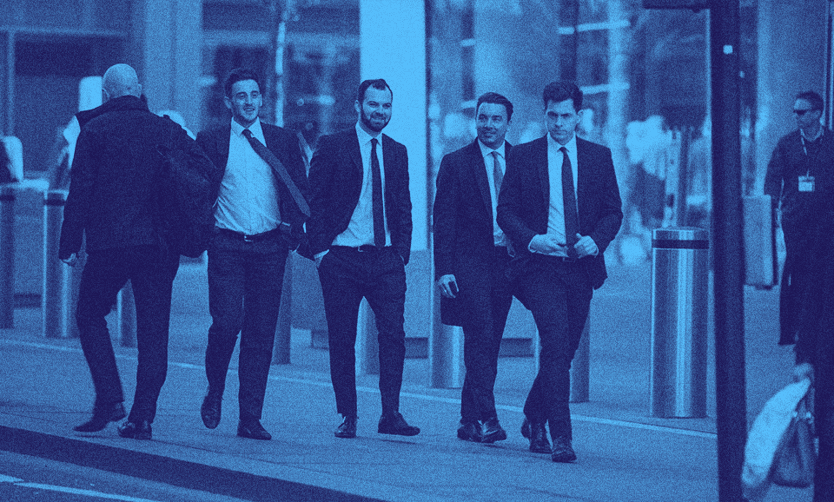 A group of men in suits walking down a street.