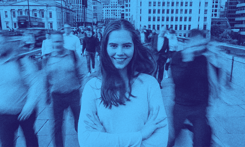 A person smiling amongst the crowd passing by her.