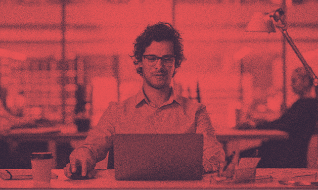 Gözlüklü bir insan, bilgisayarı başında çalışıyor