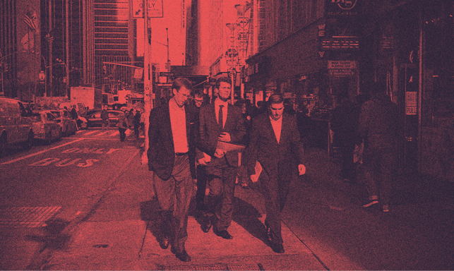 A group of men in suits walking on a street.