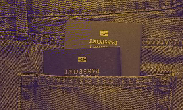 Two passports are seen stacked inside a back pocket of a person's jeans.