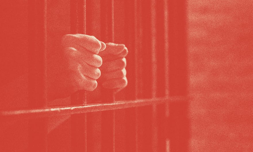 A person's hands are shown holding prison bars.