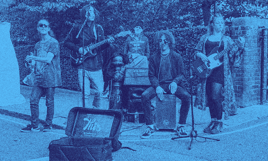 A music band performs on the sidewalk.