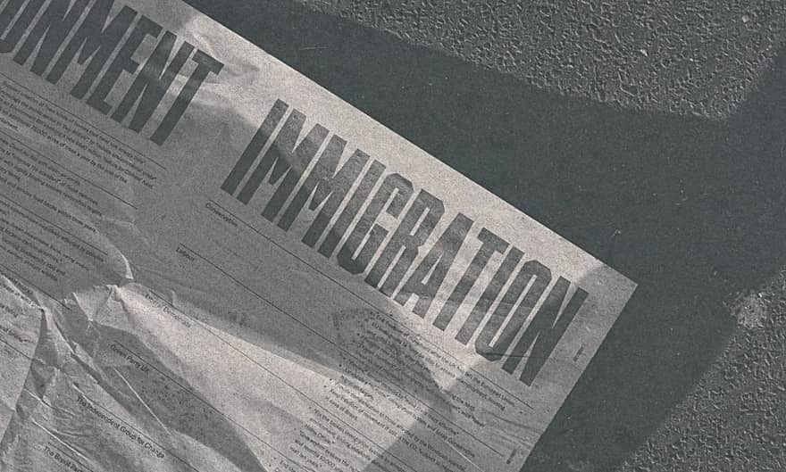 A newspaper's front page is seen laying on the street, with its main title writing "permanent immigration"