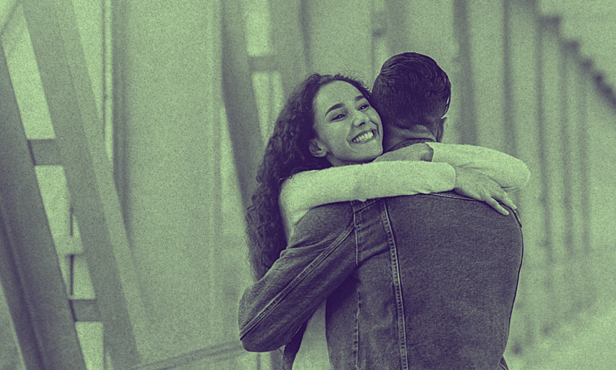 A cis couple hugging each other on a bridge.